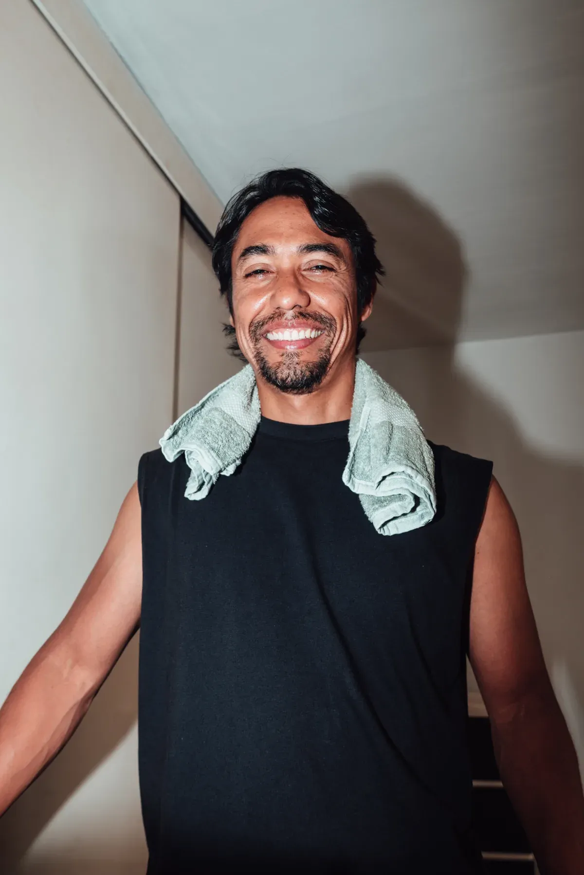 Man smiling with a towel around his neck after a workout