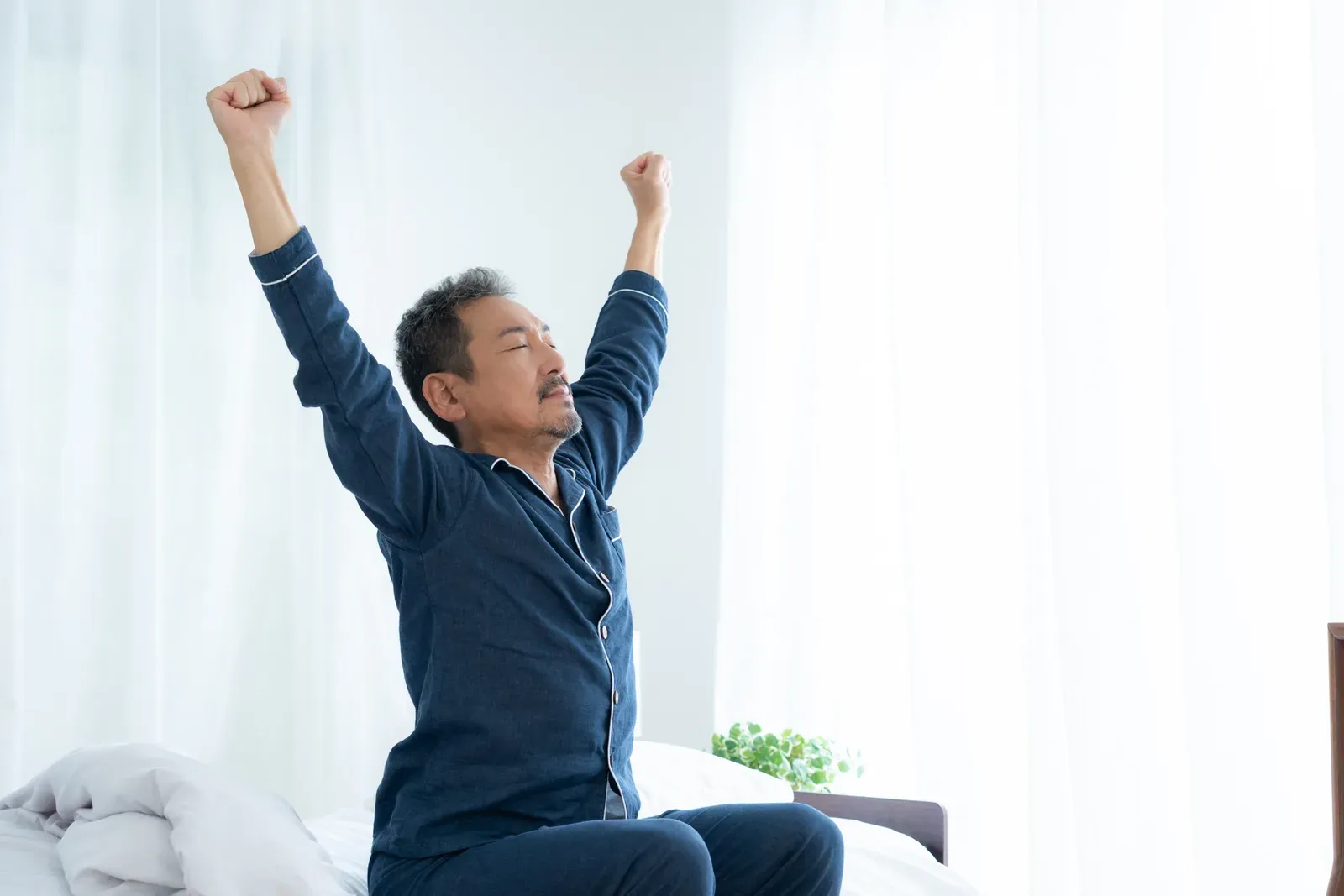 Middle-aged man stretching as he gets up in the morning