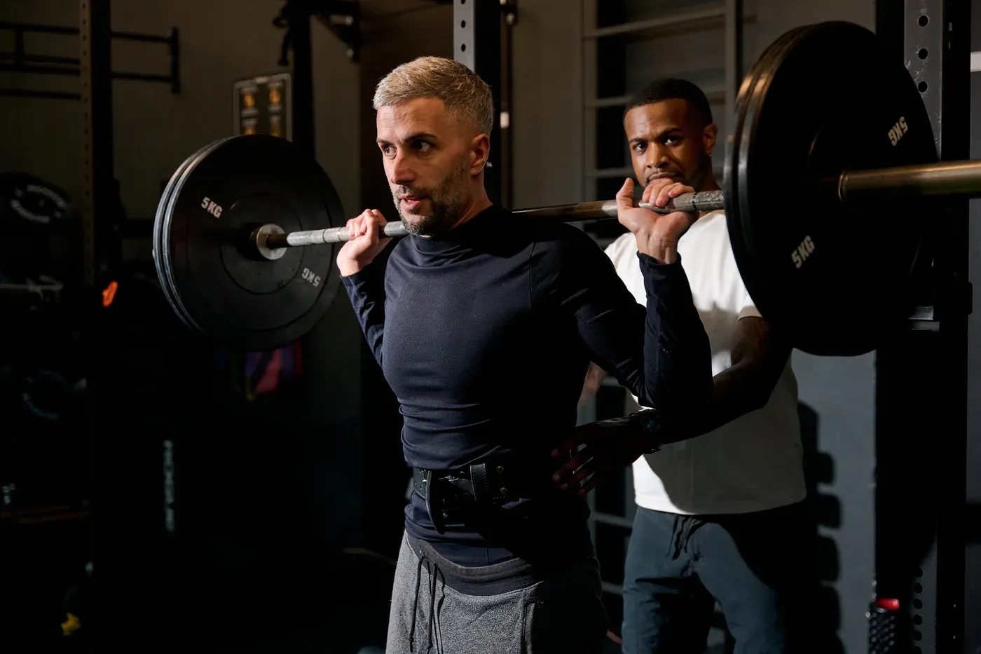 Coach spotting a man during a barbell squat