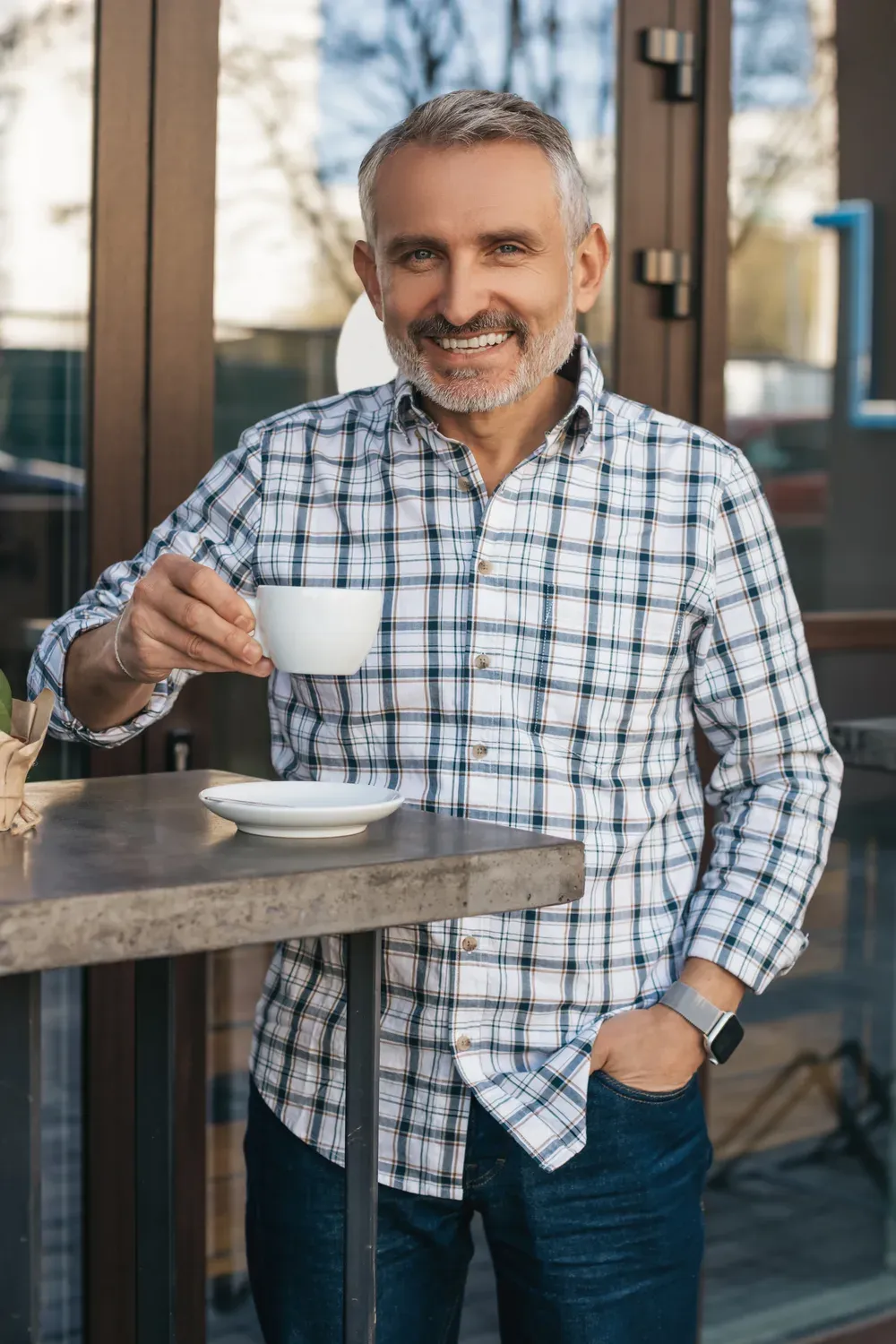 Man in his late forties smiling over a coffee at a café table